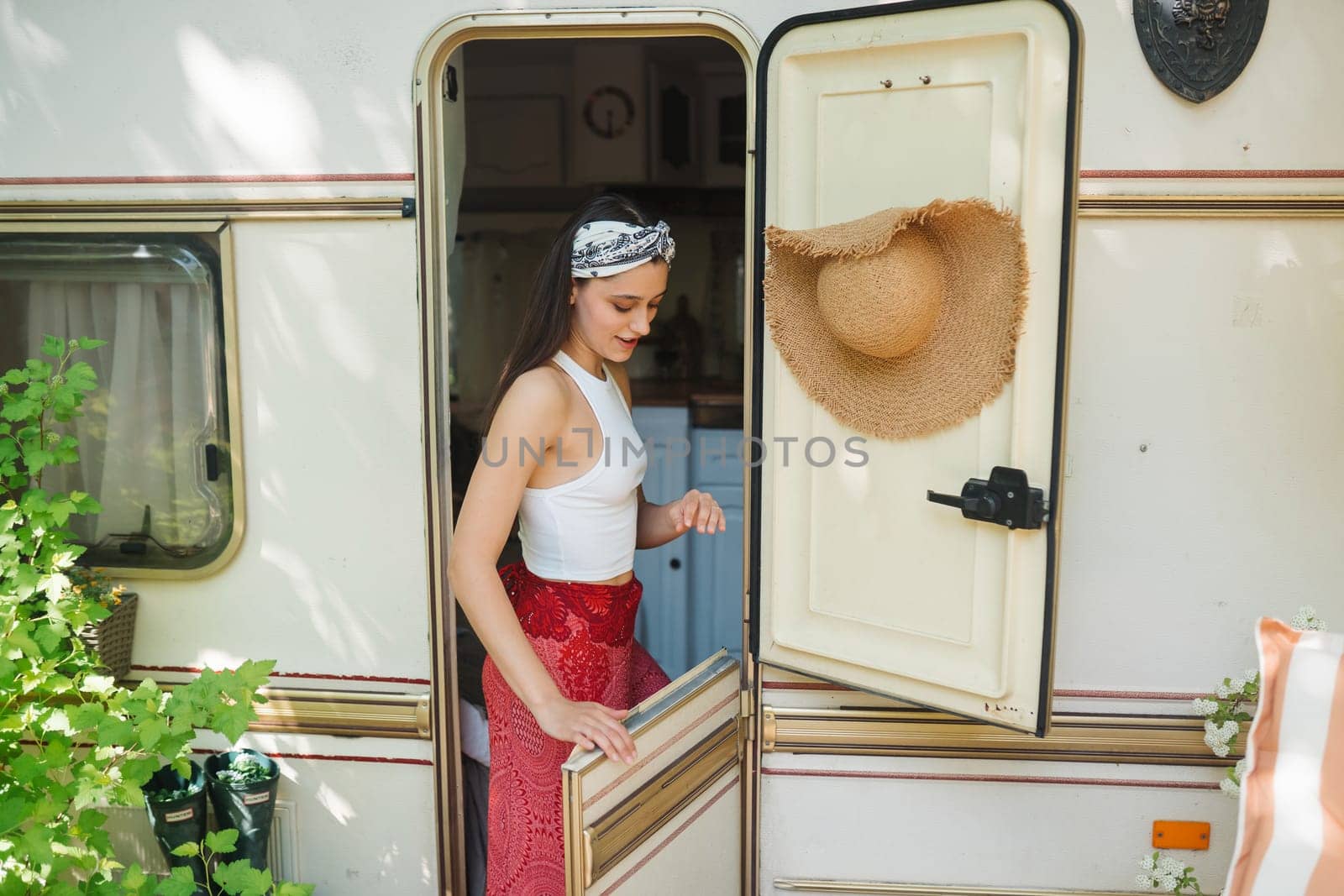 Happy hippie girl are having a good time in a camper trailer. Holiday, vacation, trip concept.High quality photo