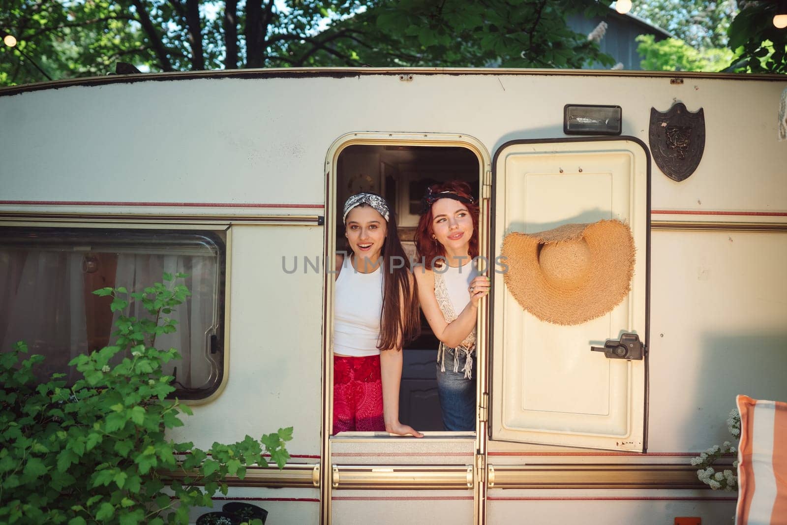 Happy hippie friends are having a good time together in a camper trailer. Holiday, vacation, trip concept. High quality photo