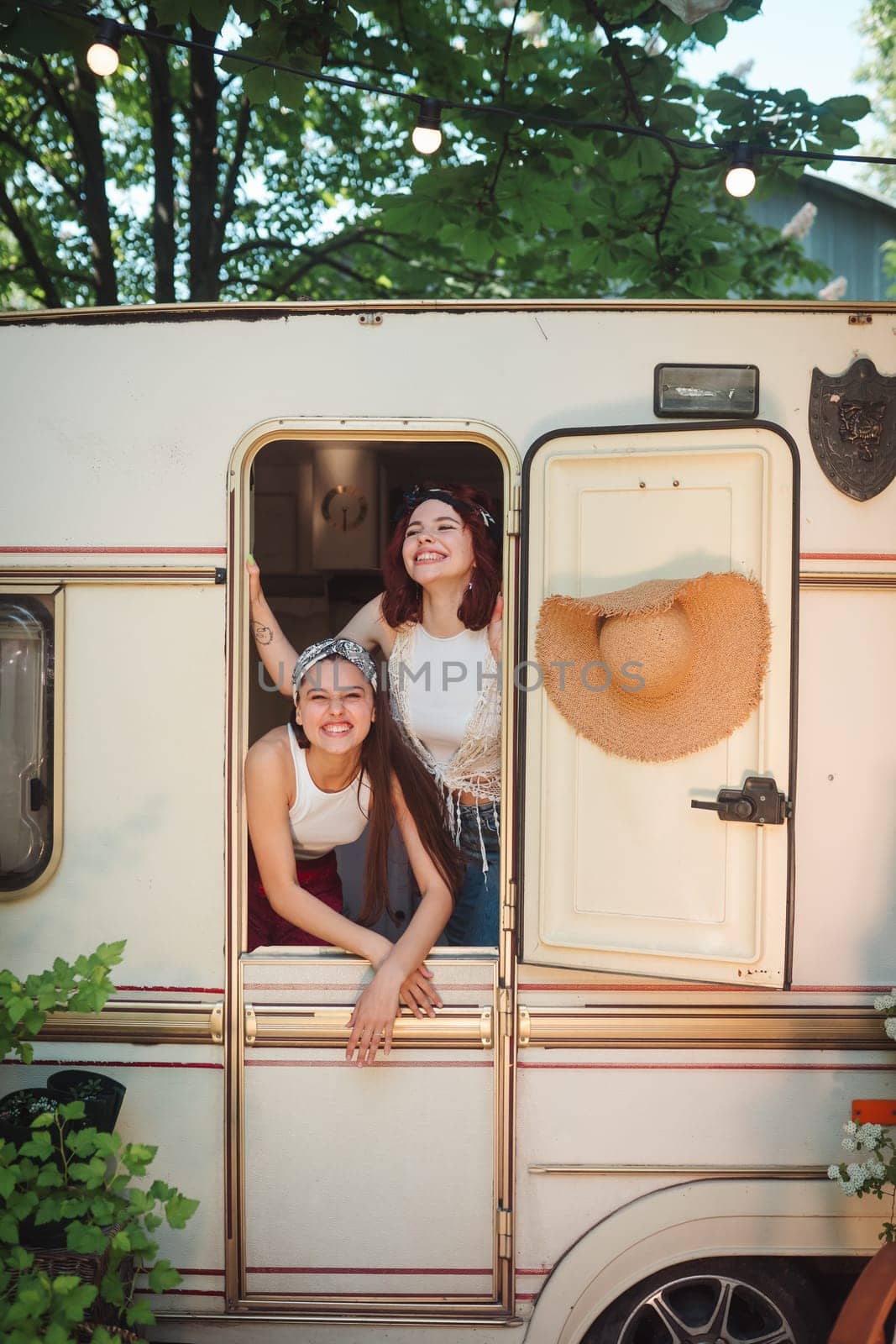 Happy hippie friends are having a good time together in a camper trailer. Holiday, vacation, trip concept. High quality photo