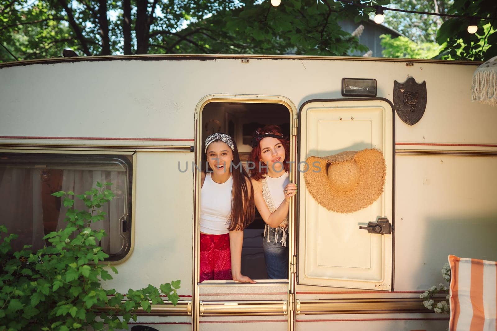 Happy hippie friends are having a good time together in a camper trailer. Holiday, vacation, trip concept. High quality photo