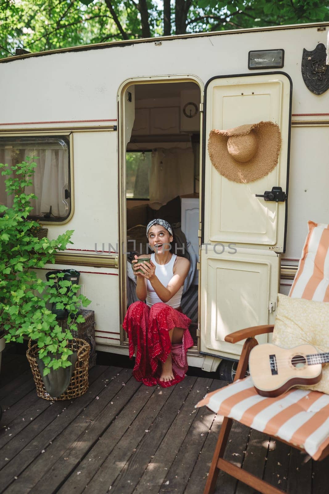 Happy hippie girl are having a good time with cup of tea in camper trailer. Holiday, vacation, trip concept.High quality photo