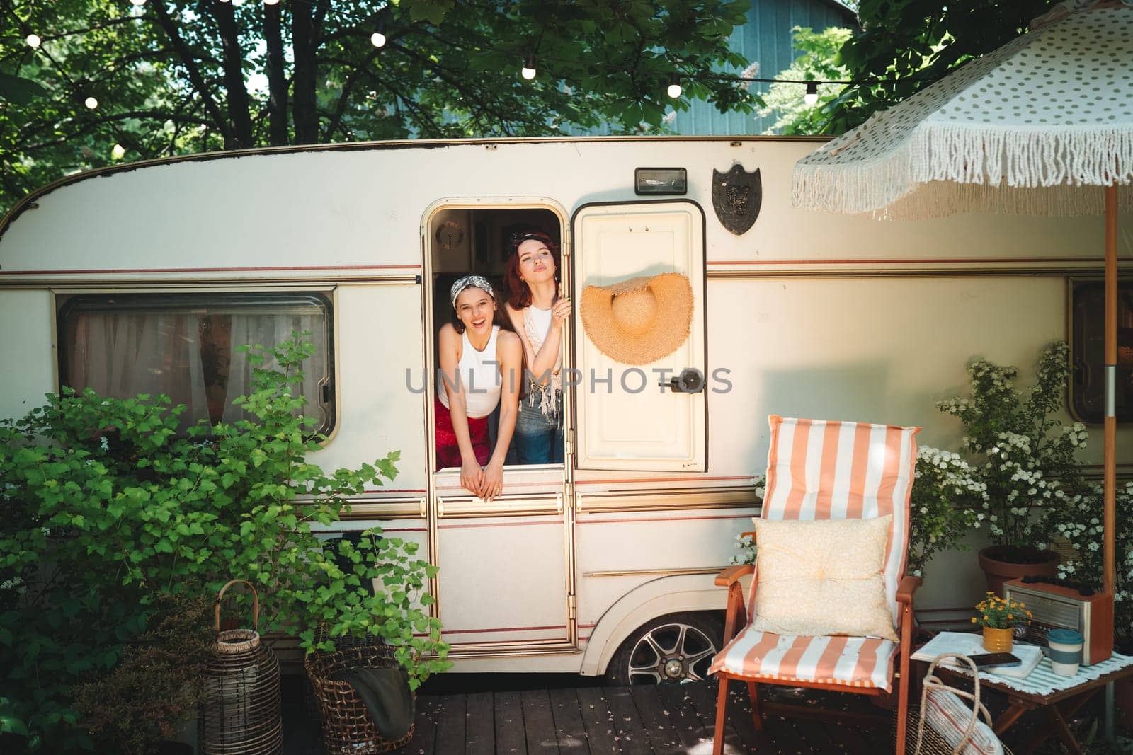 Happy hippie friends are having a good time together in a camper trailer. Holiday, vacation, trip concept. High quality photo