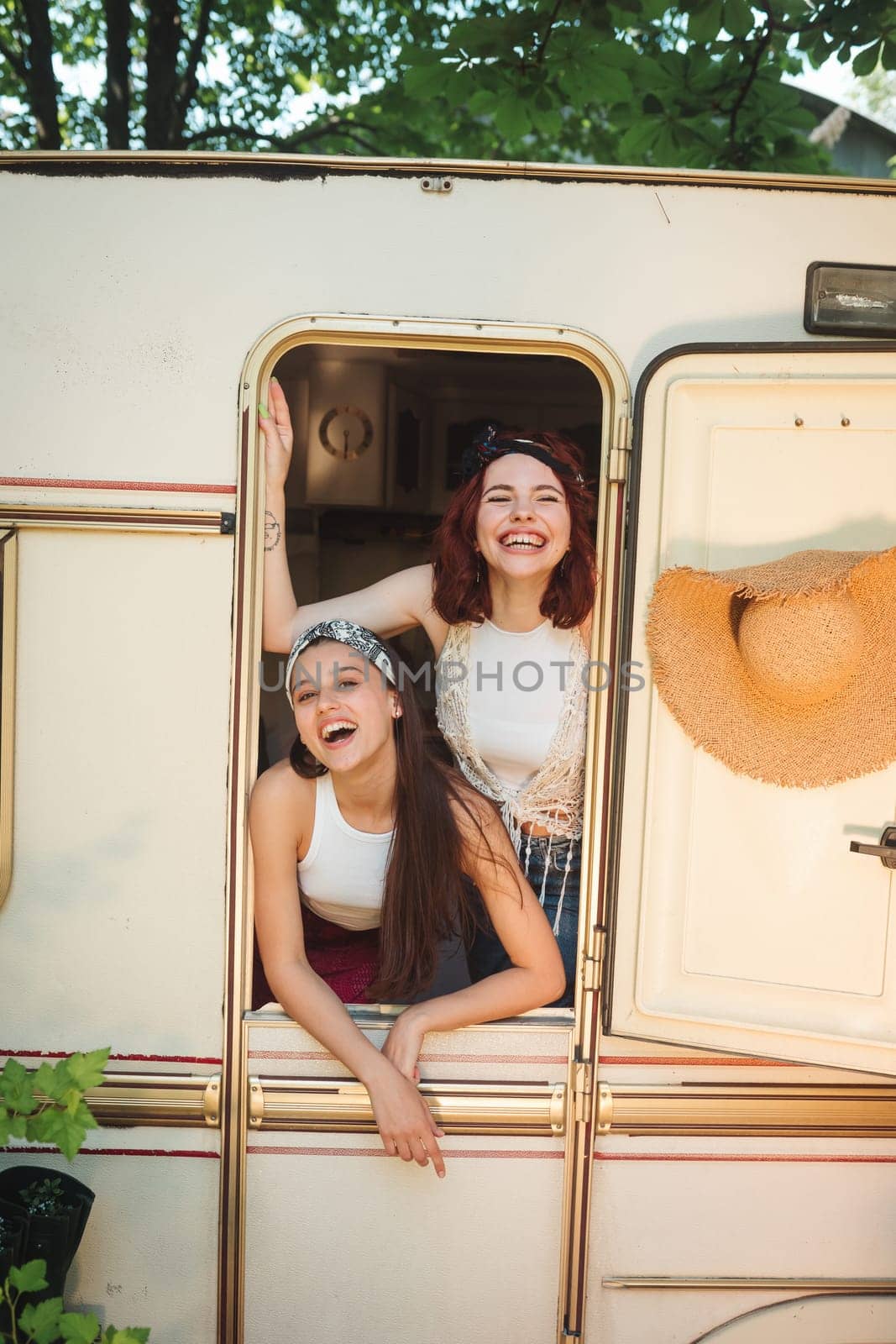 Happy hippie friends are having a good time together in a camper trailer. Holiday, vacation, trip concept. High quality photo