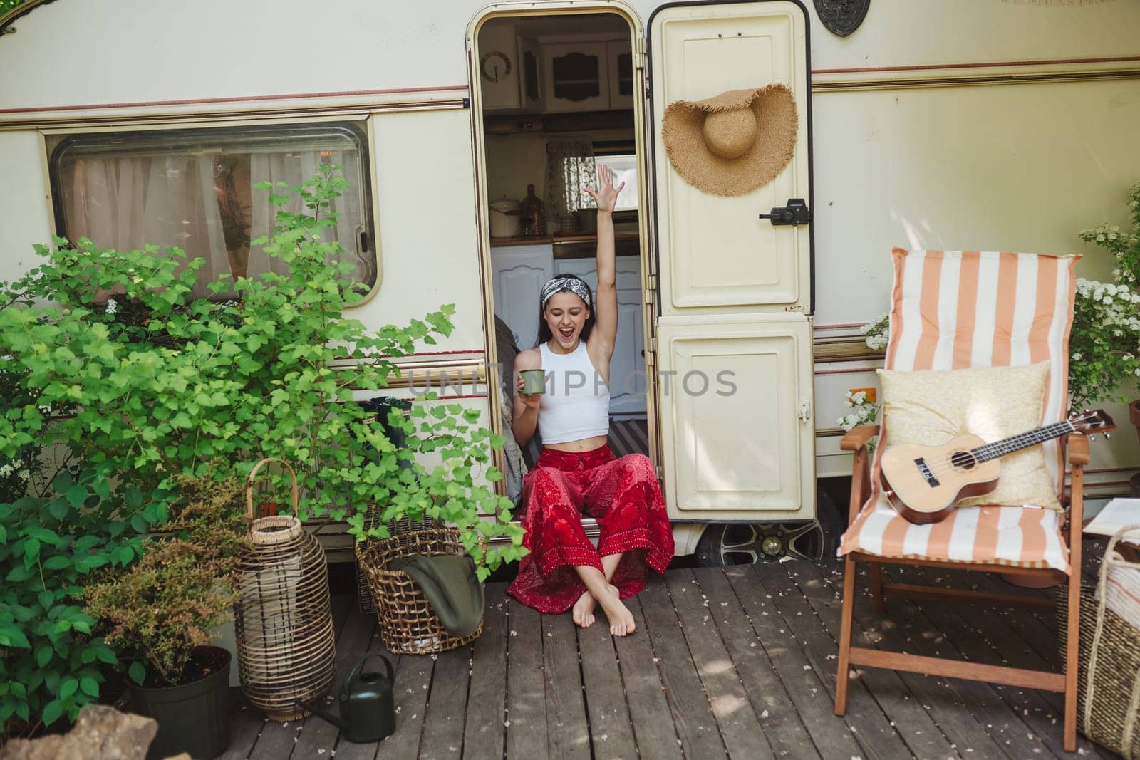 Happy hippie girl are having a good time with cup of tea in camper trailer. Holiday, vacation, trip concept.High quality photo