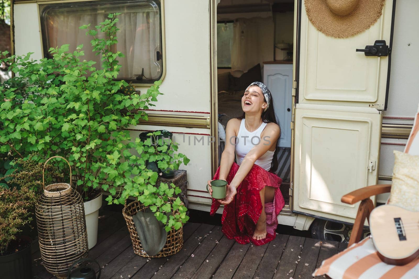 Happy hippie girl are having a good time with cup of tea in camper trailer. Holiday, vacation, trip concept.High quality photo