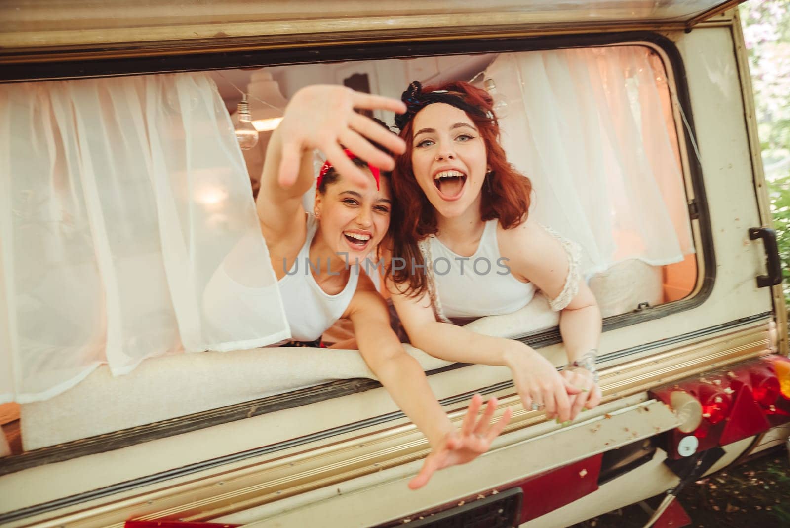 Happy hippie friends are having a good time together in a camper trailer. Holiday, vacation, trip concept. High quality photo