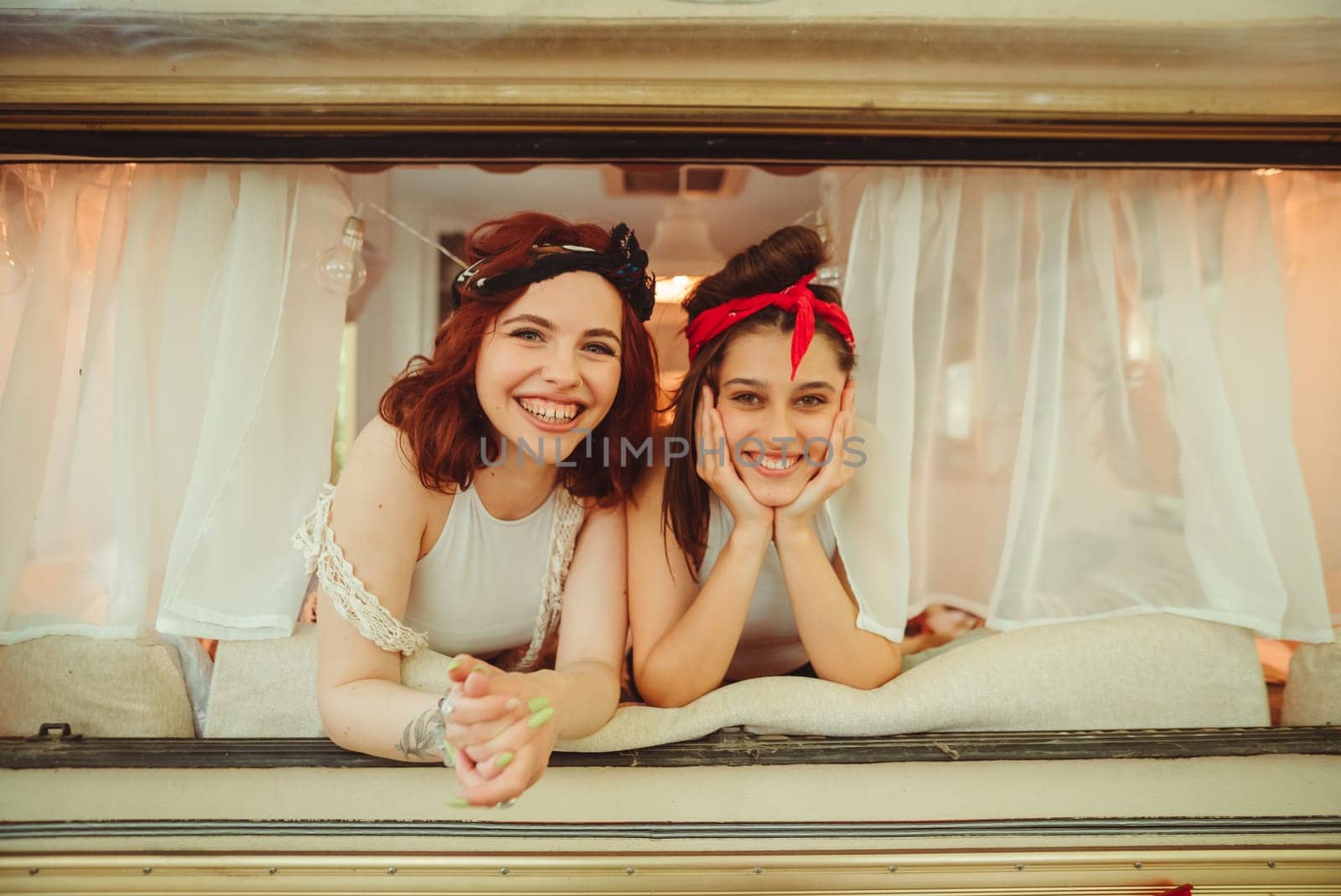 Happy hippie friends are having a good time together in a camper trailer. Holiday, vacation, trip concept. High quality photo