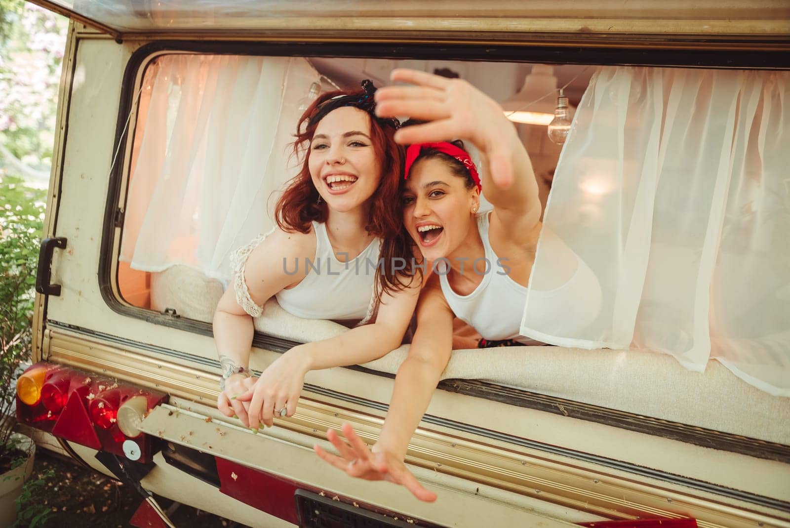 Happy hippie friends are having a good time together in a camper trailer. Holiday, vacation, trip concept. High quality photo