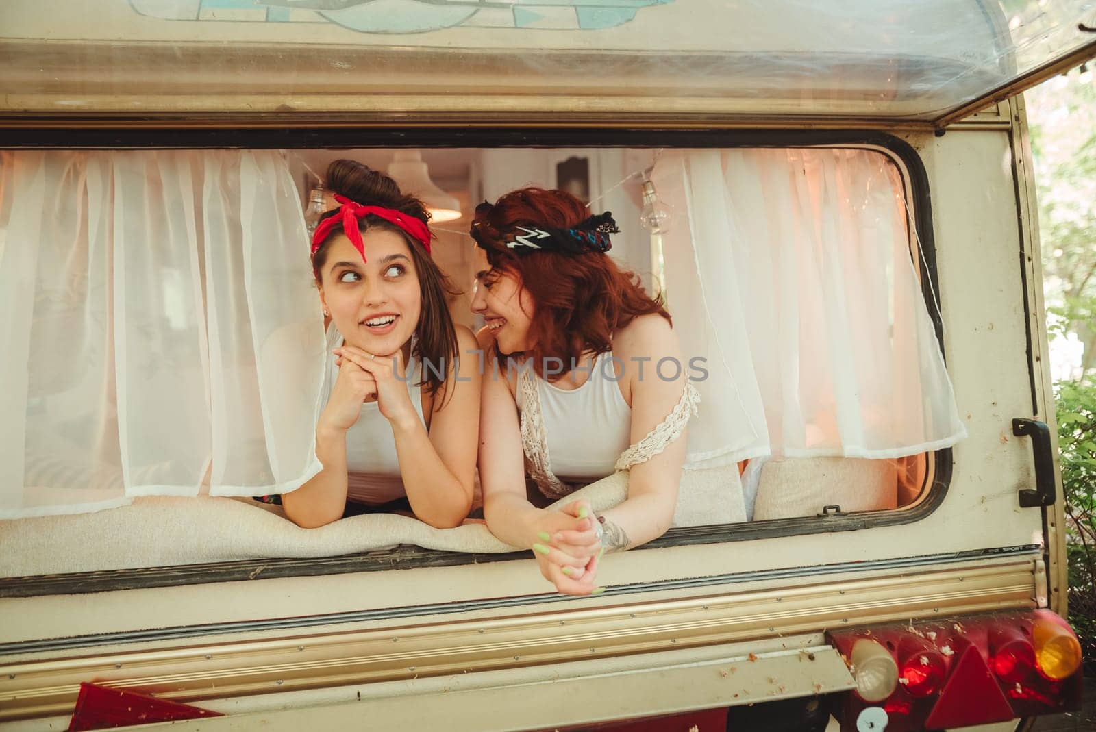 Happy hippie friends are having a good time together in a camper trailer. Holiday, vacation, trip concept. High quality photo