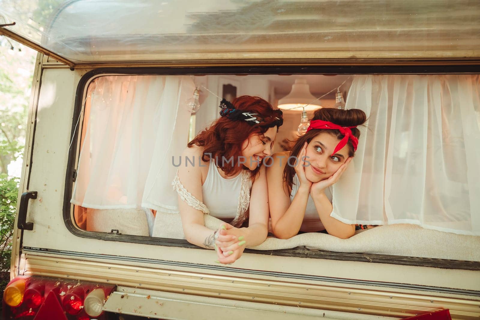 Happy hippie friends are having a good time together in a camper trailer. Holiday, vacation, trip concept. High quality photo