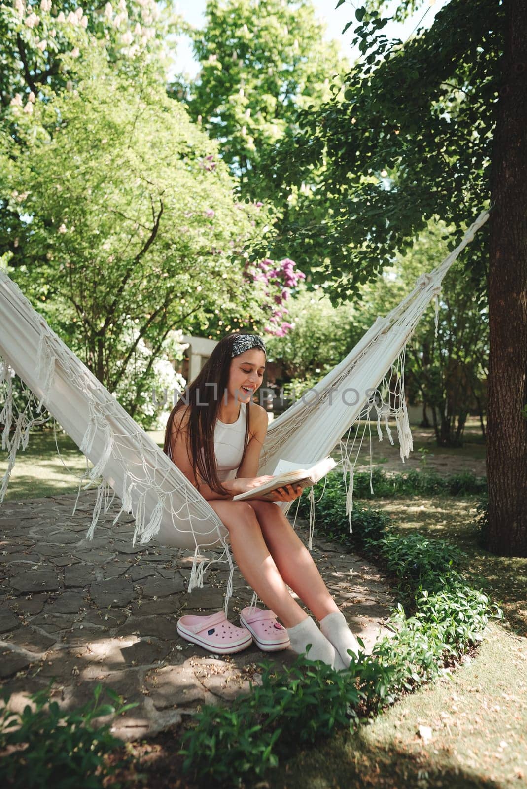 Happy hippie girl is reading a book in hammock having a good time with playing in camper trailer. Holiday, vacation, trip concept.High quality photo