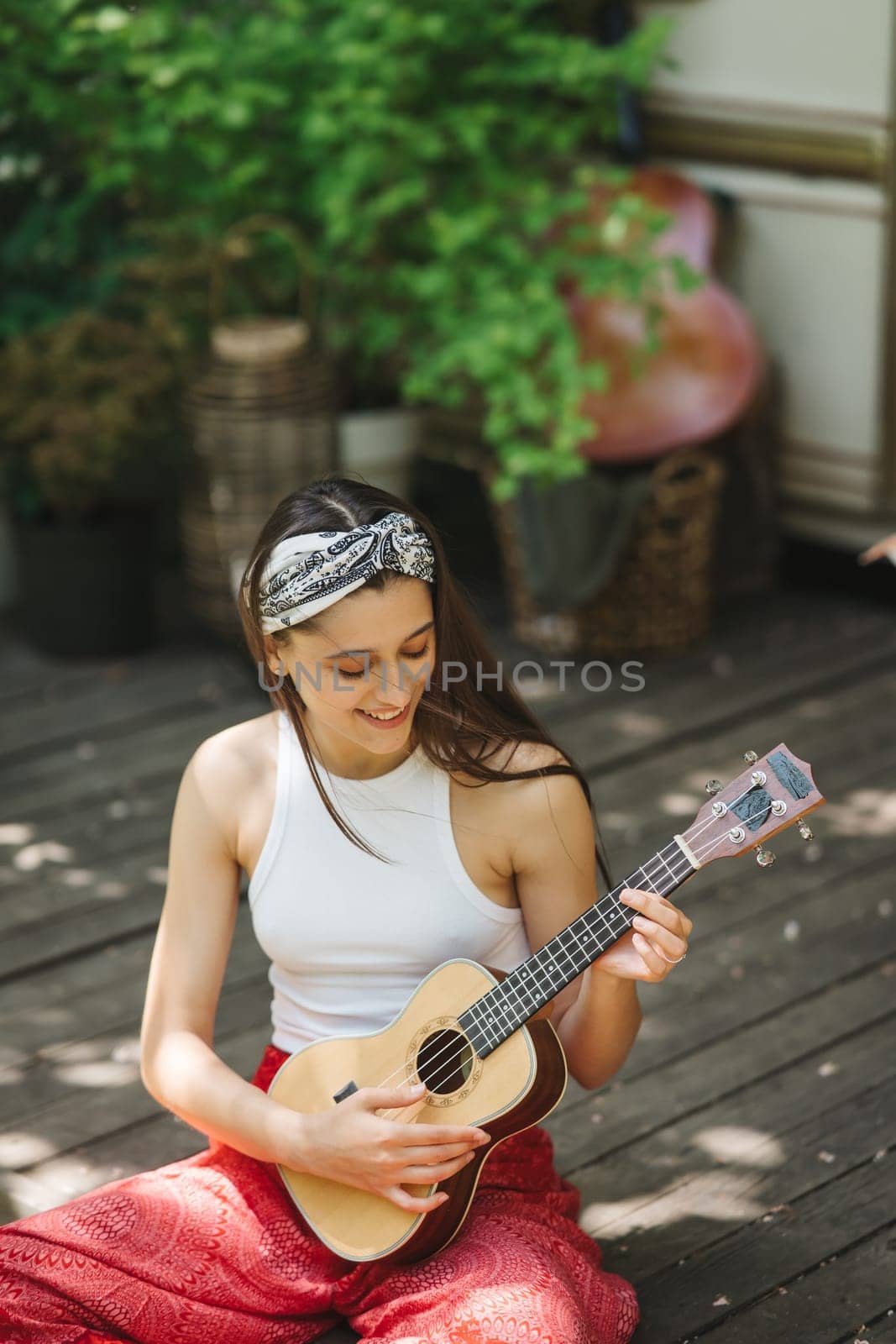 Happy hippie girl are having a good time with playing on guitar in camper trailer. Holiday, vacation, trip concept.High quality photo