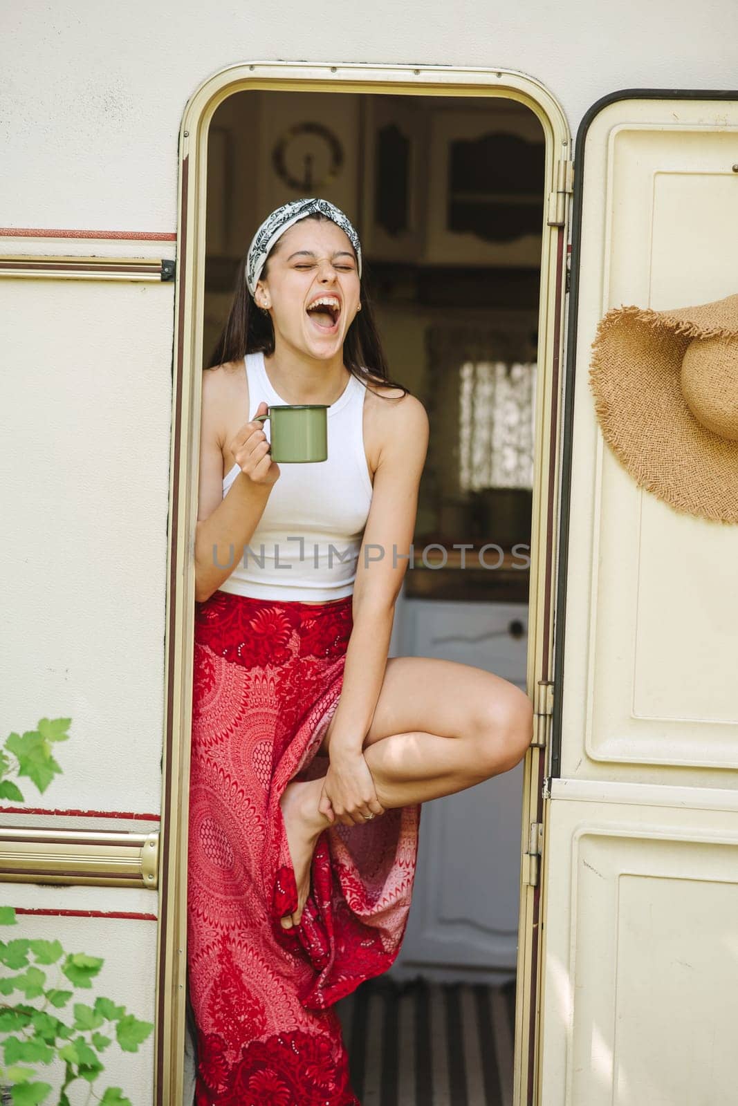 Happy hippie girl are having a good time with cup of tea in camper trailer. Holiday, vacation, trip concept.High quality photo