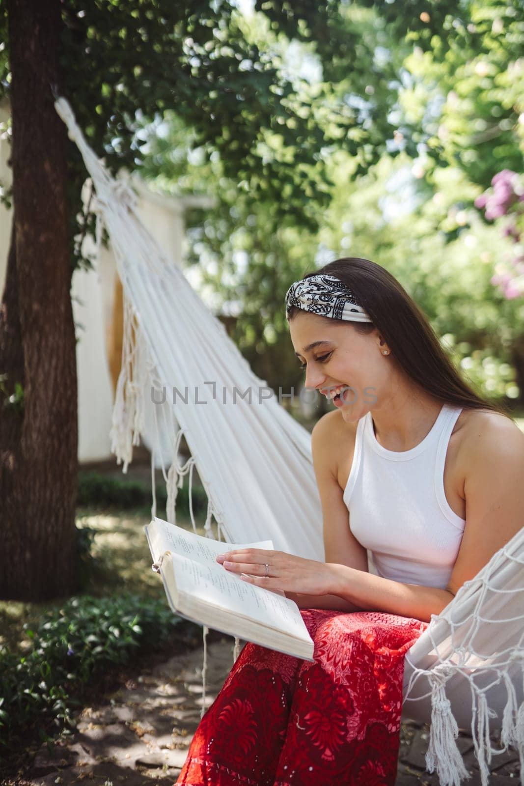 Happy hippie girl is reading a book in hammock having a good time with playing in camper trailer. Holiday, vacation, trip concept.High quality photo