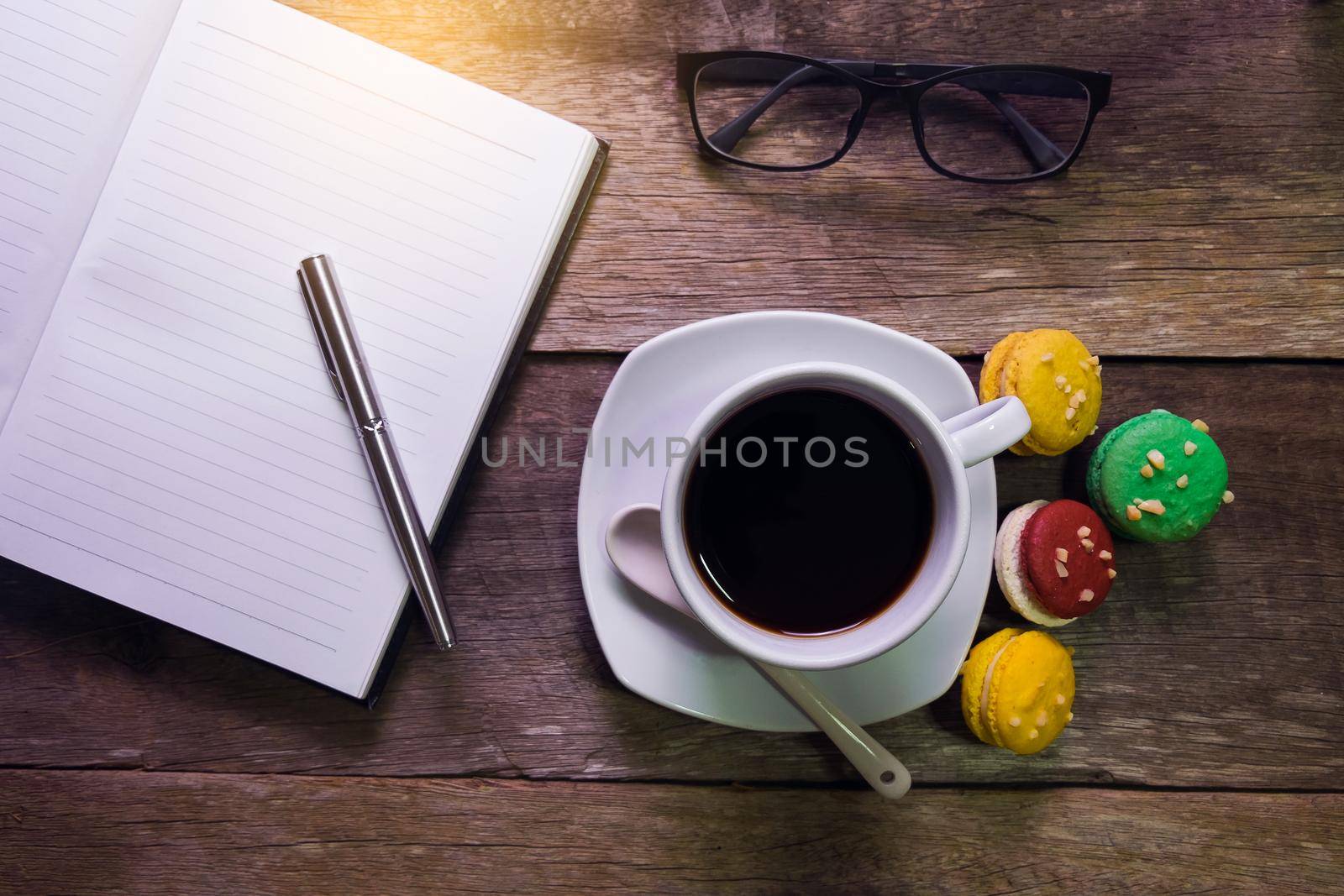 notebook on rustic wood with macaroon cup of coffee and glasses