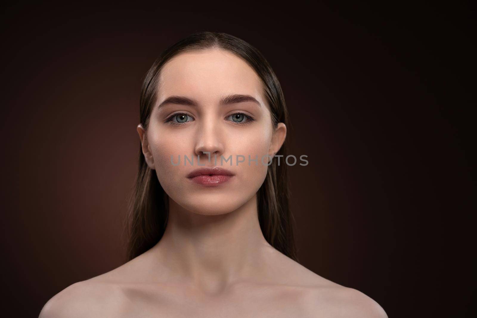 Strong look girl face portrait with natural make up and bare shoulders. Healthy pure skin model isolated on black background. Natural make up concept. Spa and beautiful concept.