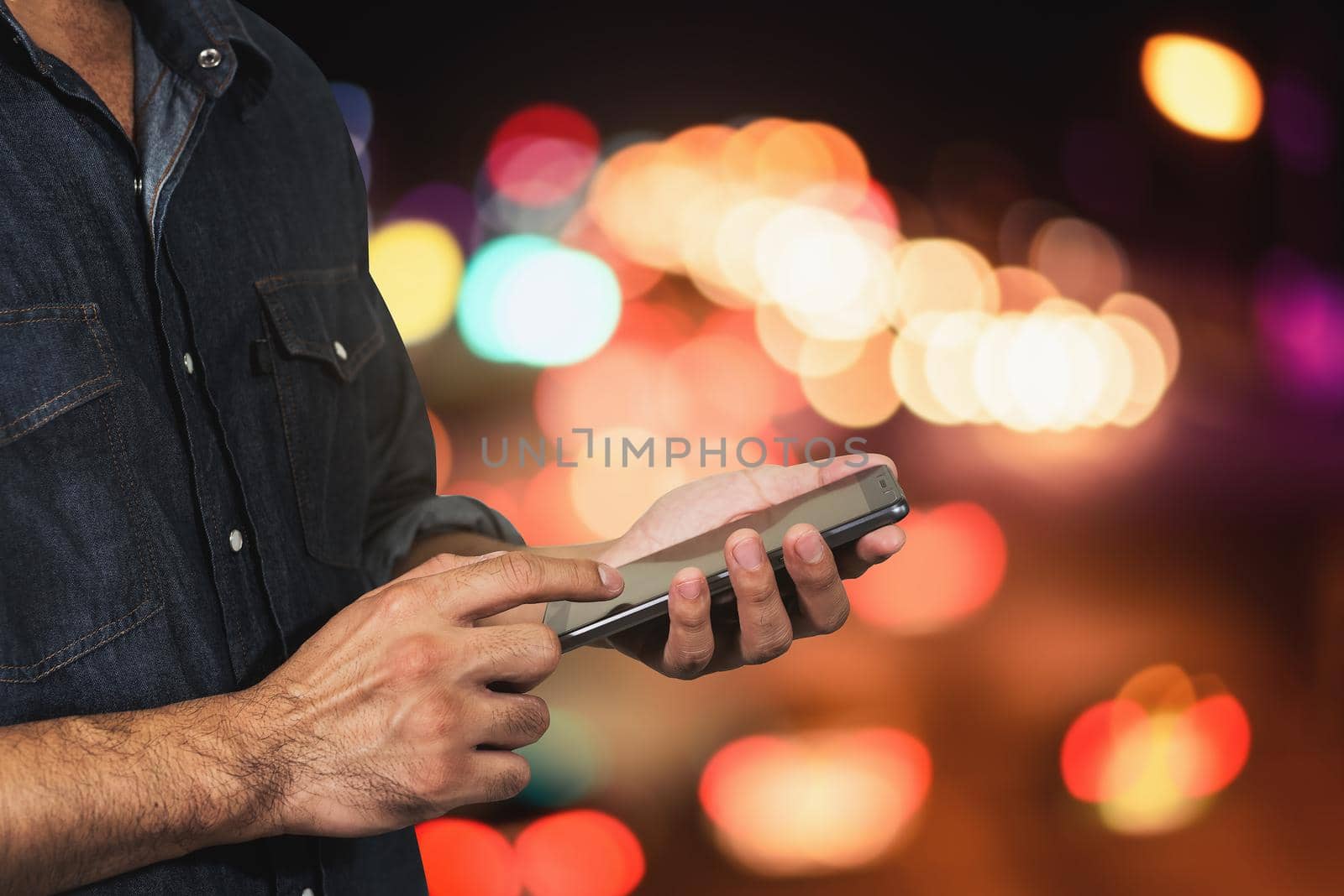 Man using his mobile Phone night light bokeh background by Wmpix
