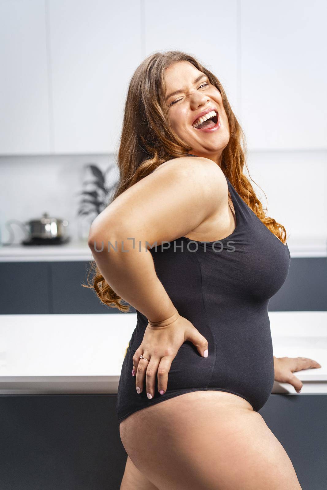 Young fat woman trying diet. Girl standing next to the kitchen table. Diet young fat woman standing on kitchen. Close up chubby female lowering BMI weight. Trying to loose weight fast. 