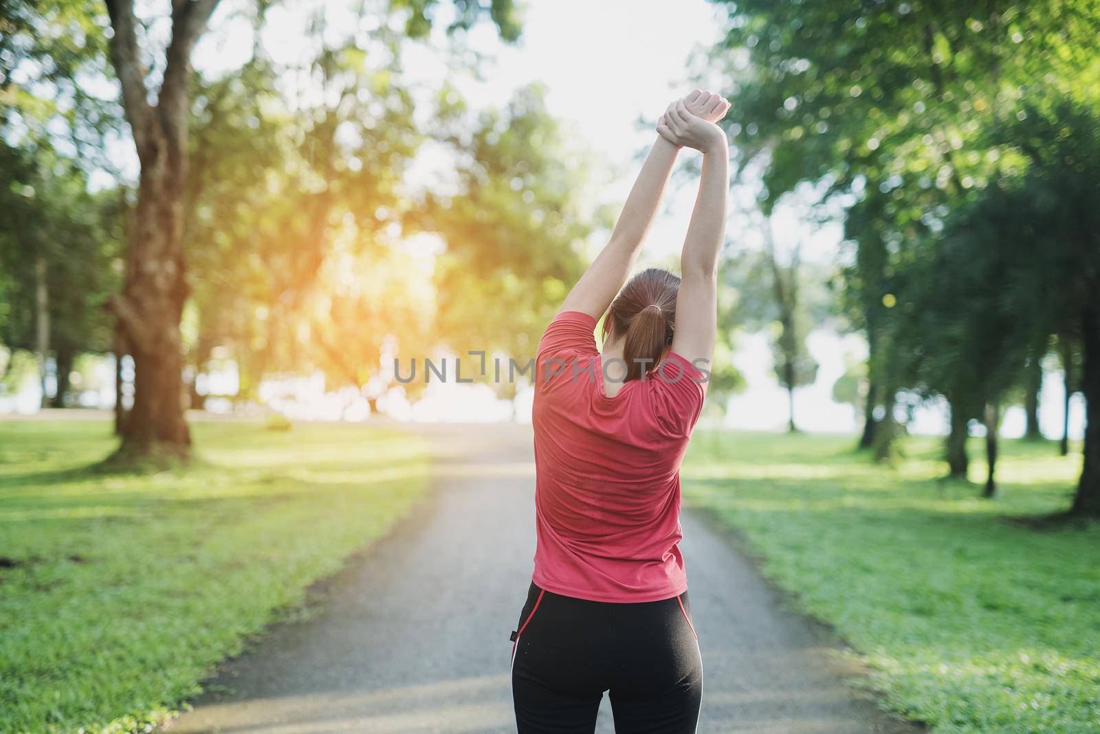 young asian woman doing exercise outdoor in day light, stretching. by Wmpix