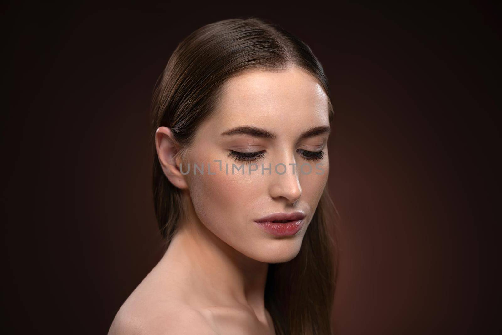 Strong and lowered gaze close up portrait with no make up. Healthy pure skin model isolated on black background. Natural make up concept. Spa and beautiful concept by LipikStockMedia