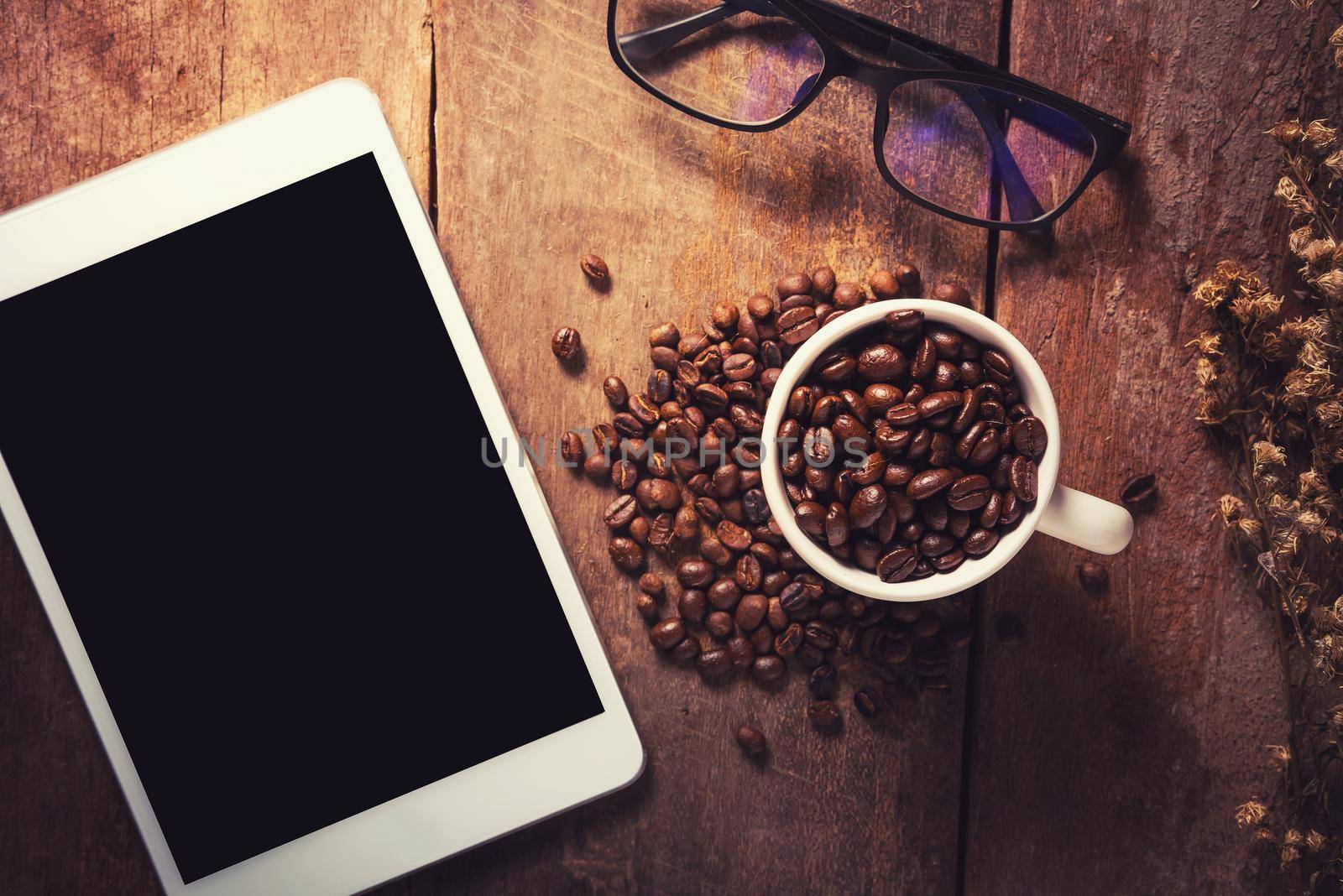 Tablet with coffee beans and glasses on wood table, Vintage color by Wmpix