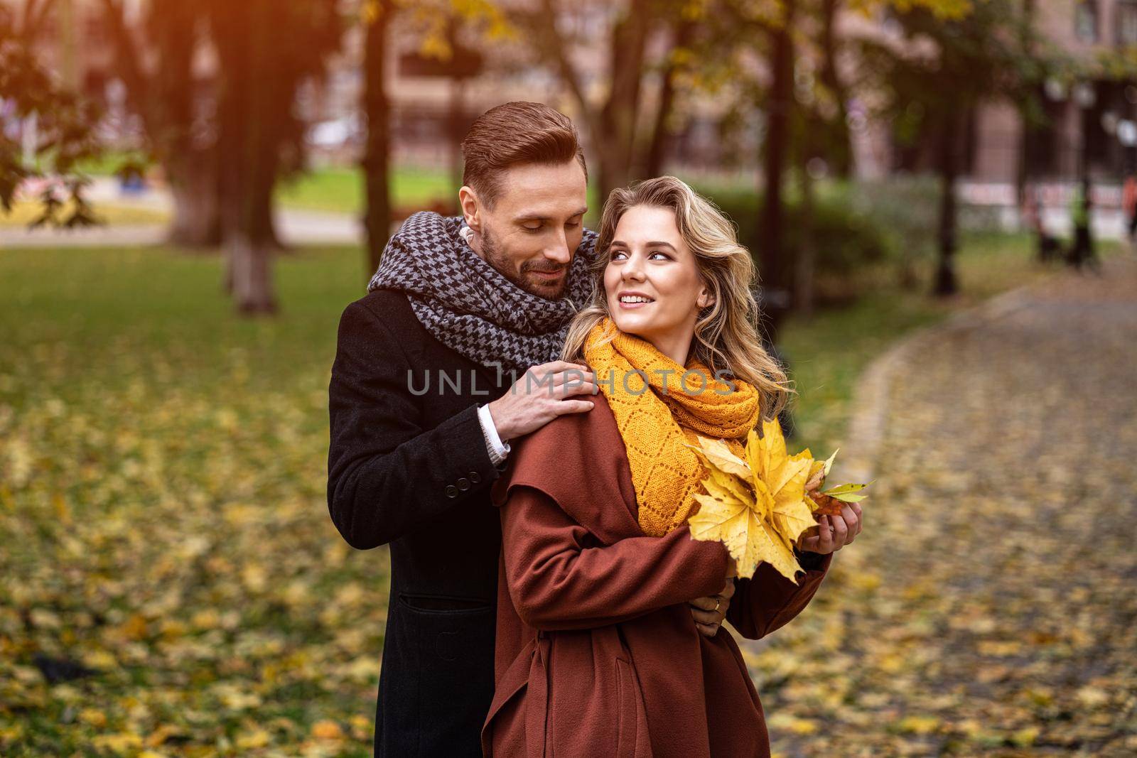 Loving couple in an autumn park. Husband and a wife smile looking at each other in the autumn park. Outdoor shot of a young couple in love having great time in a autumn park.