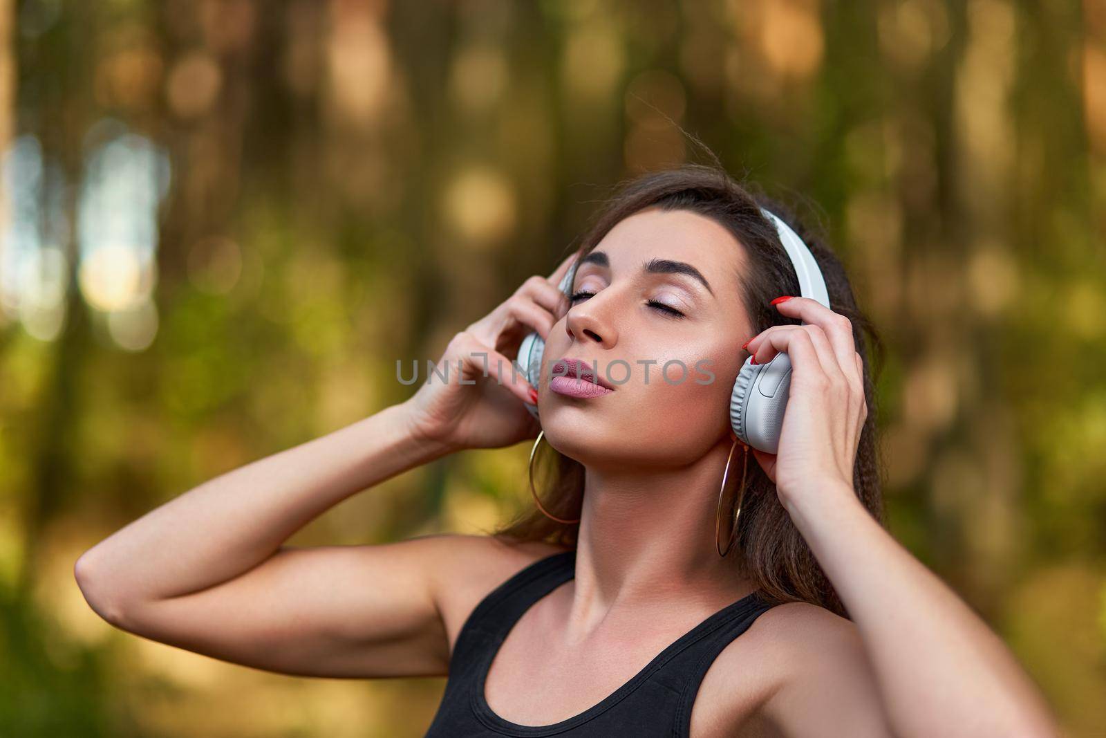 Young woman listening to music in the forest. by AliaksandrFilimonau