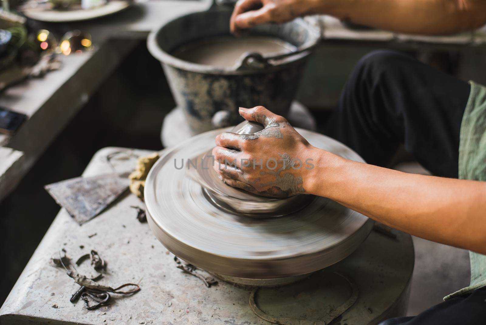 Closeup potter's hands shaping soft clay to make an earthen pot by Wmpix