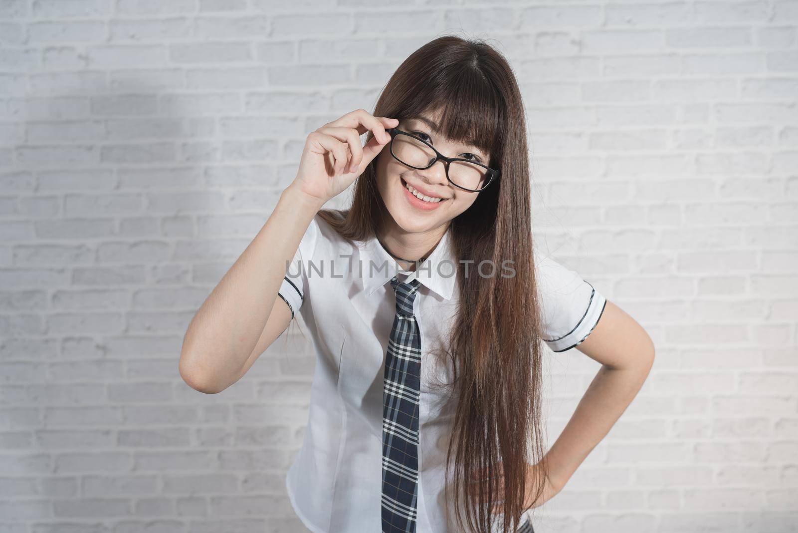 Portrait of cute student girl wearing japan uniform on gray background by Wmpix