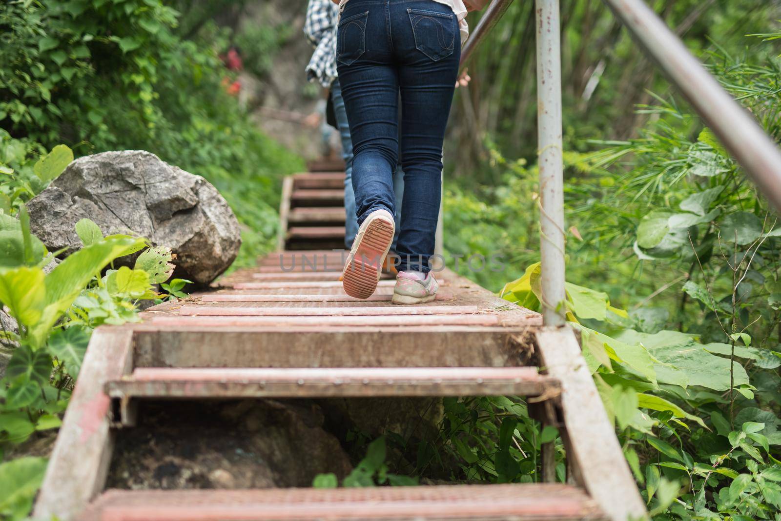 women wearing jeans and sneakers step on old wooden bridge by Wmpix
