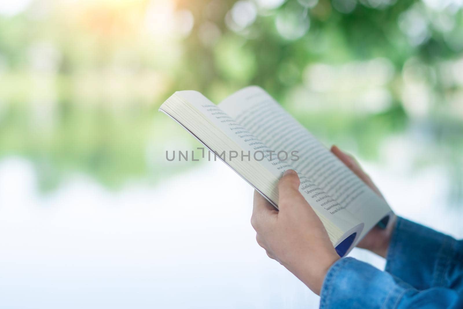 Woman is reading book in beautiful park and pond relax and peaceful environment background.