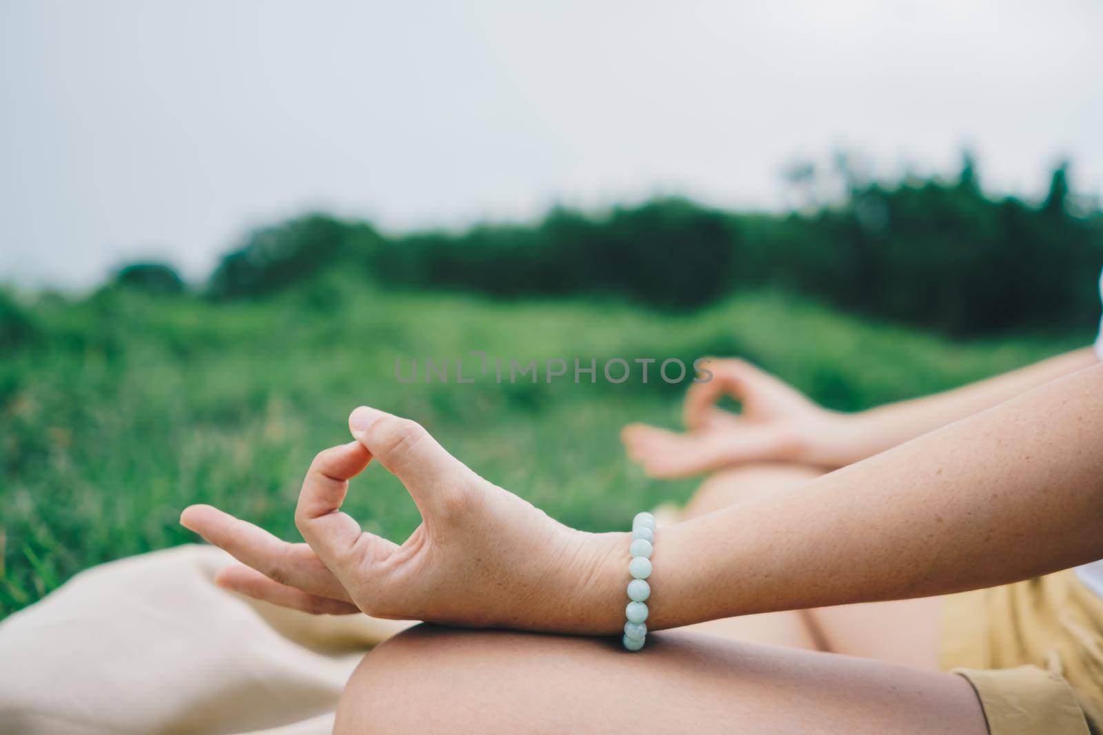 Woman practicing yoga lesson, breathing, meditating exercise, outdoor in grass field. Well being, wellness concept