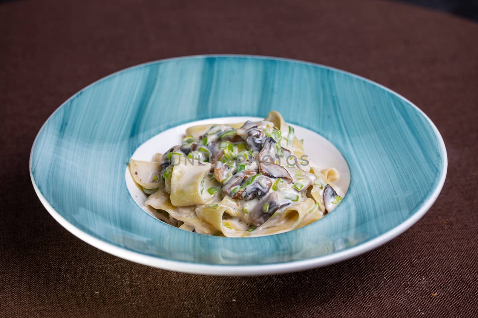 pasta with mushrooms and sauce in a blue plate by Pukhovskiy