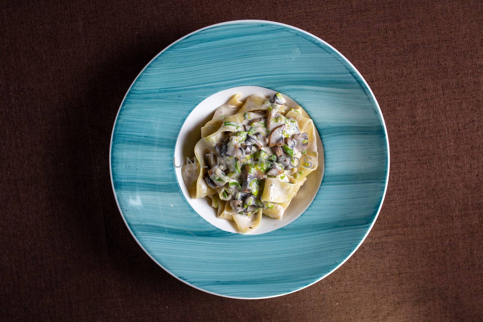 top view pasta with mushrooms and sauce in a blue plate by Pukhovskiy