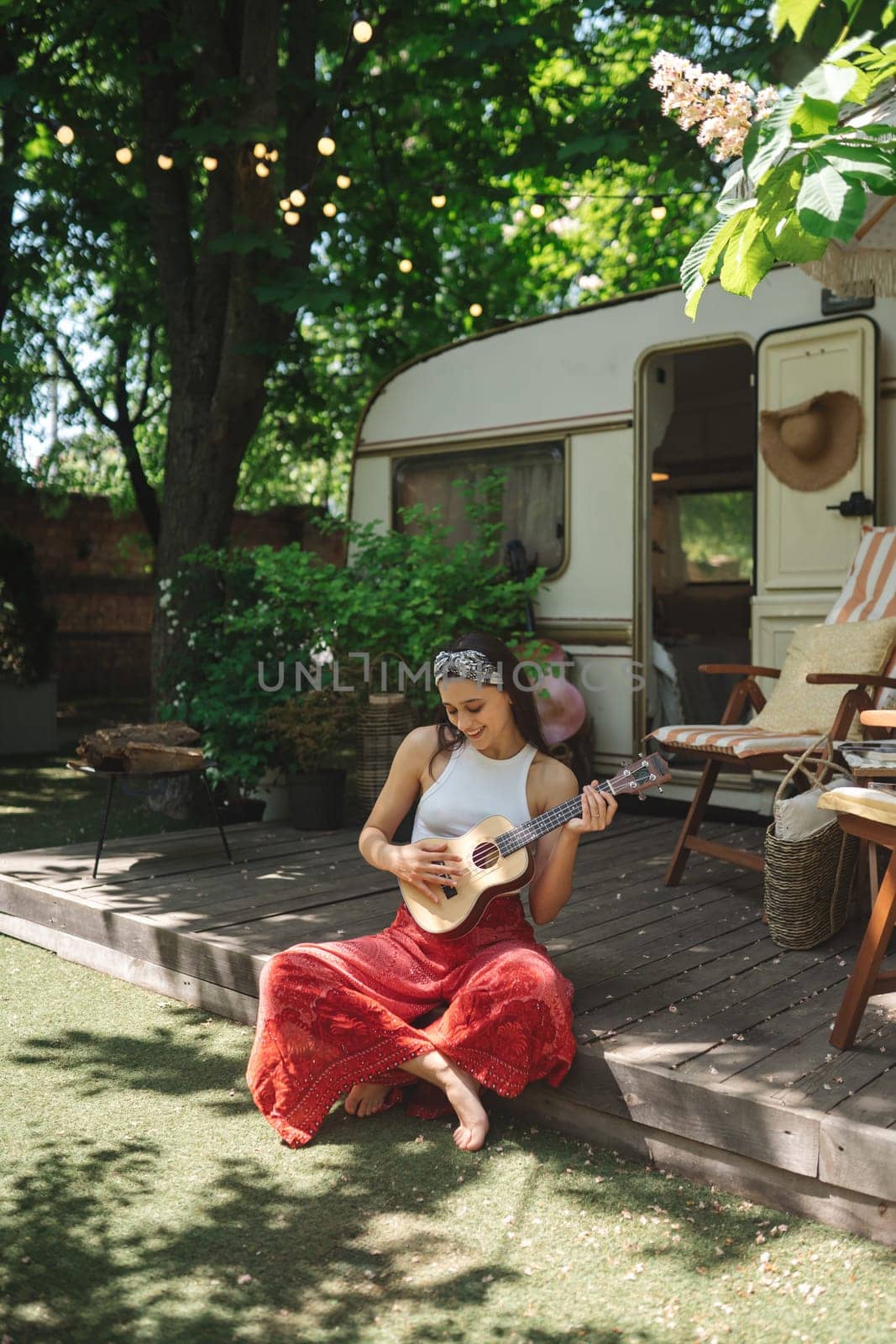 Happy hippie girl are having a good time with playing on guitar in camper trailer. Holiday, vacation, trip concept.High quality photo