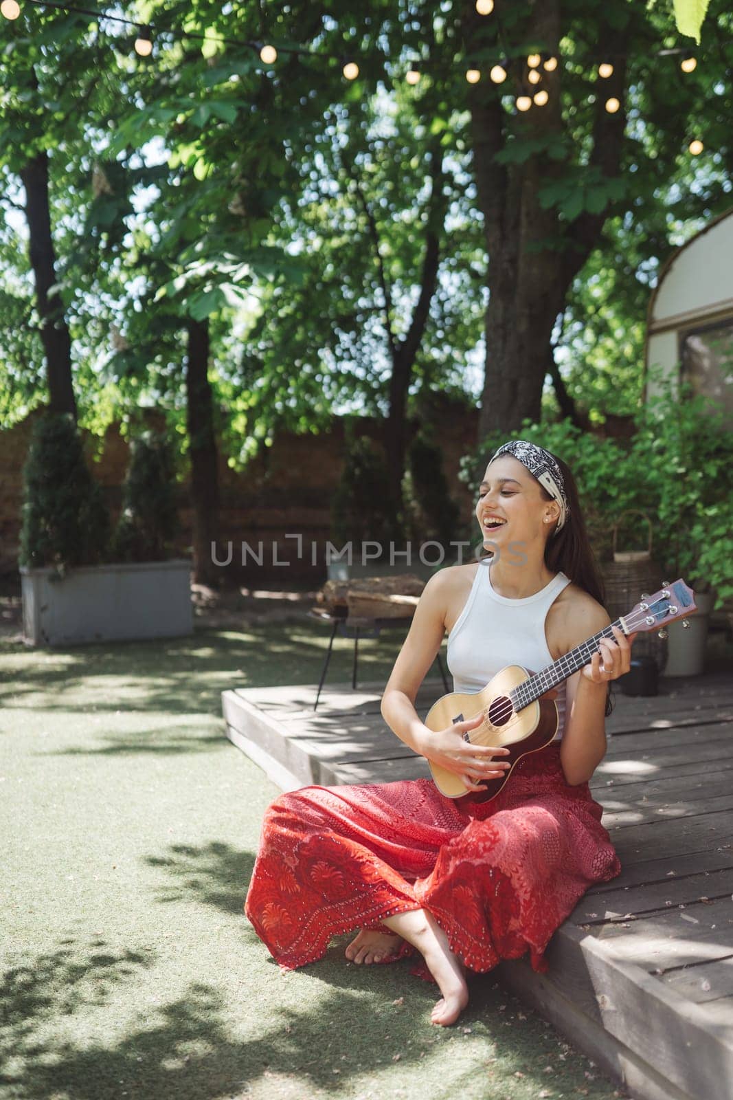 Happy hippie girl are having a good time with playing on guitar in camper trailer. Holiday, vacation, trip concept.High quality photo