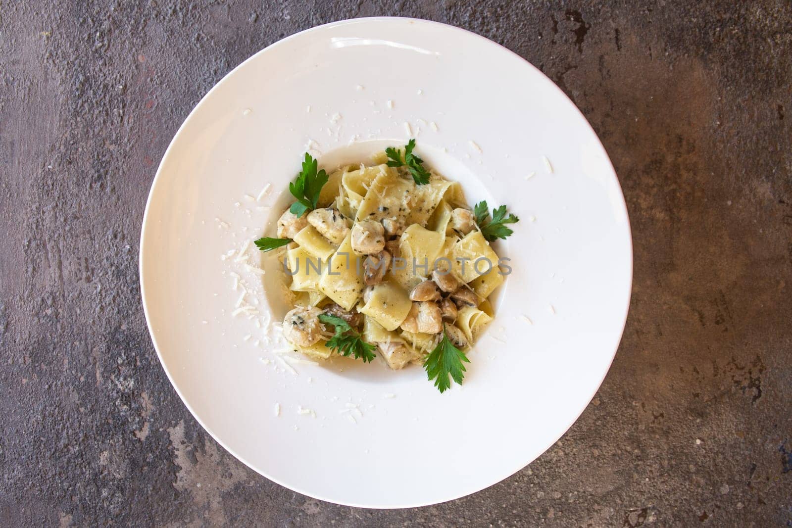 top view pasta with chicken and herbs in a white plate.