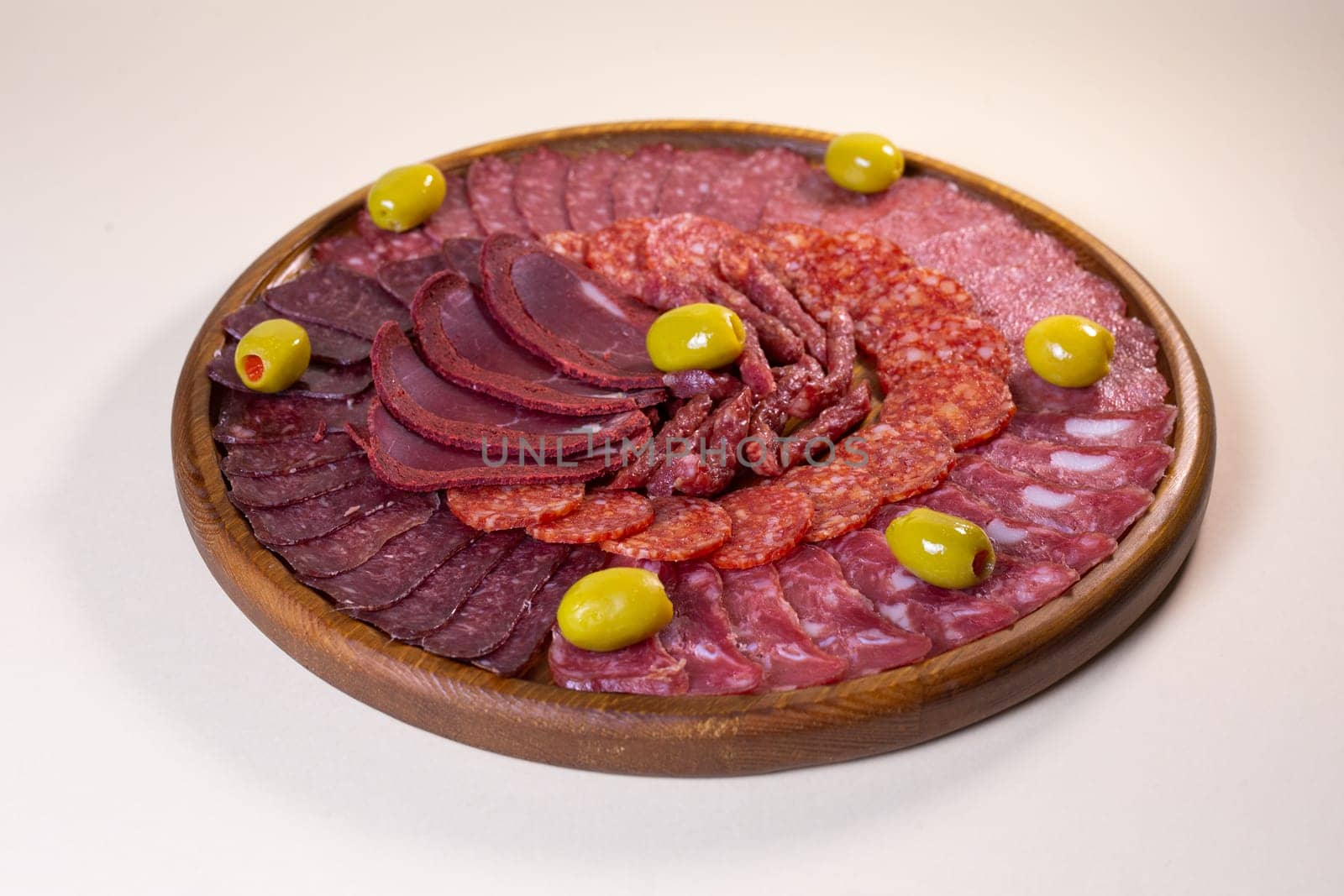 cold cuts of sausage delicacies on a wooden round stand.