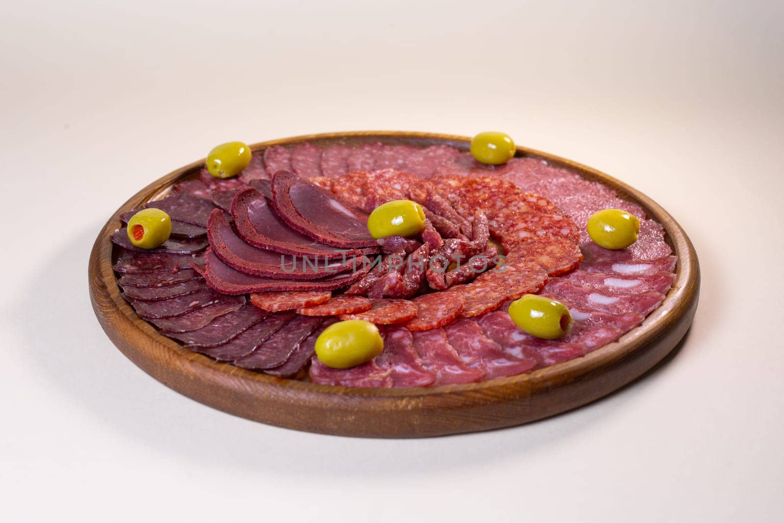 cold cuts of sausage delicacies on a wooden round stand by Pukhovskiy