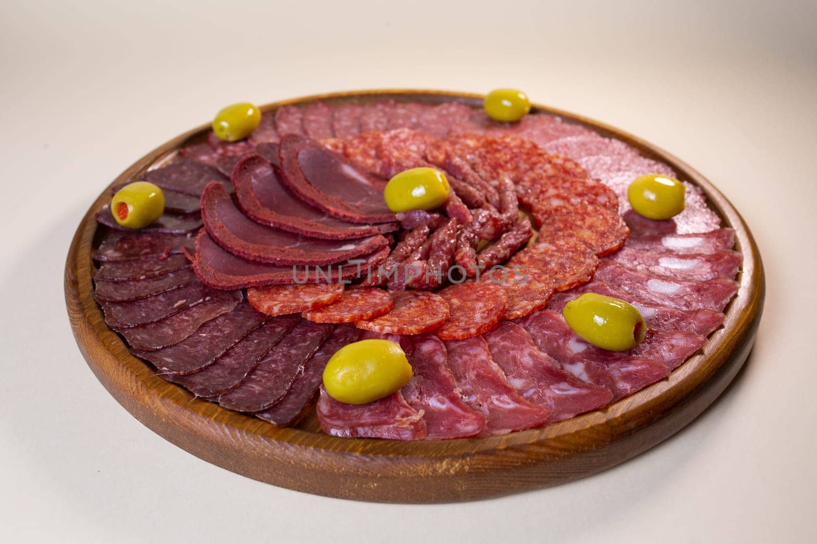 cold cuts of sausage delicacies on a wooden round stand.