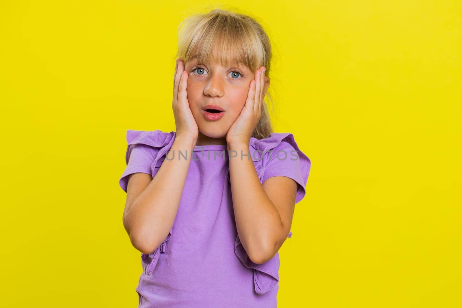 Oh my God, Wow. Young preteen child girl kid looking surprised at camera with big eyes, shocked by sudden victory game winning lottery goal achievemen good news. Children isolated on yellow background