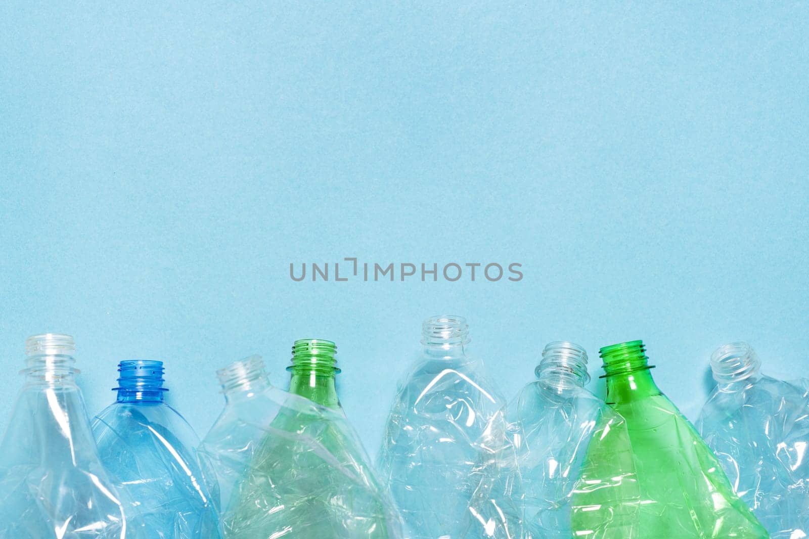 Flat set crushed bottle crumpled plastic bottle recycling background trash plastic garbage PET recycling design blue paper. Row empty bottle PET plastic recycling concept. Used. Reuse. Waste sorting by synel