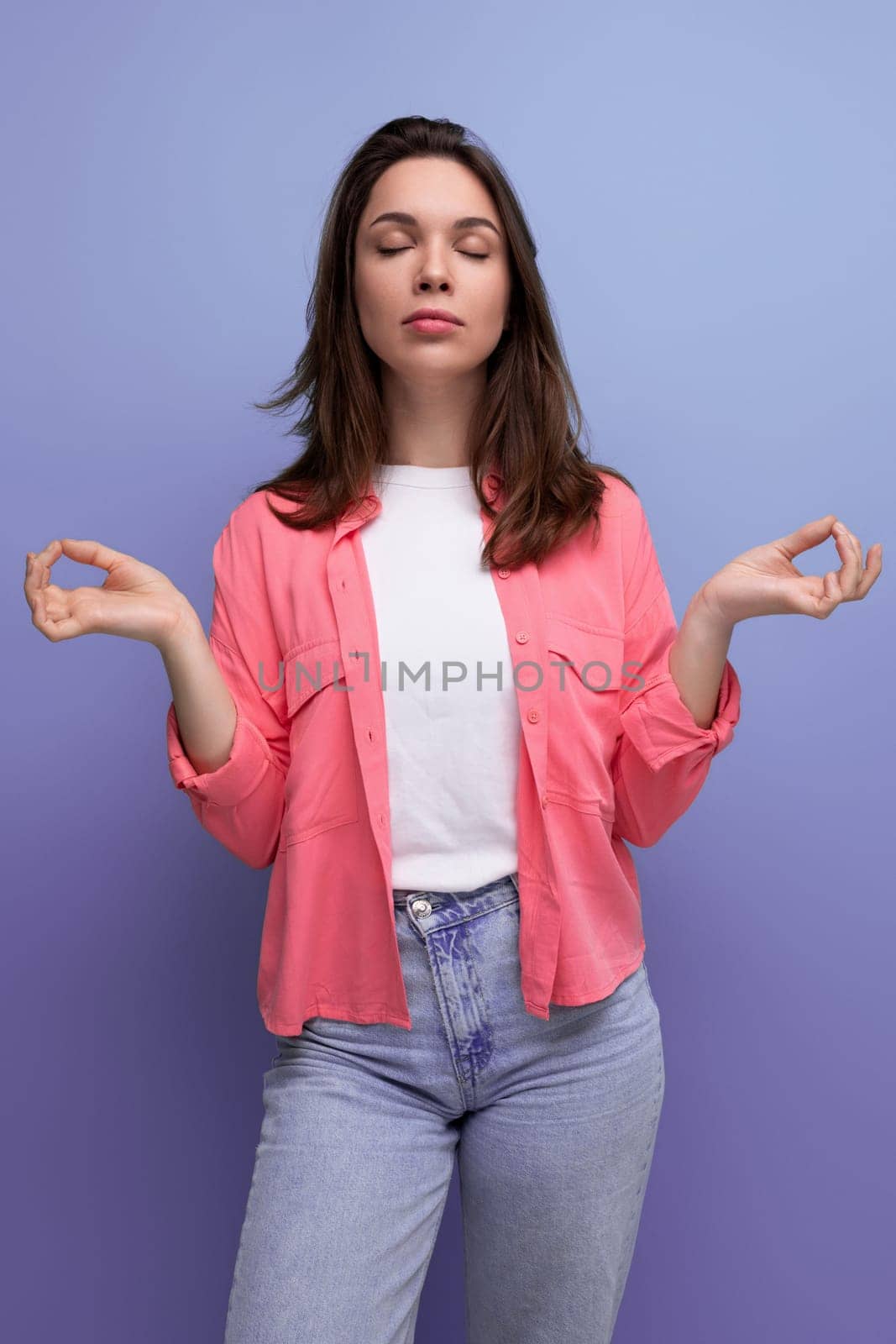 a pleasant brunette woman with hair below her shoulders in a shirt is in balance and calm.