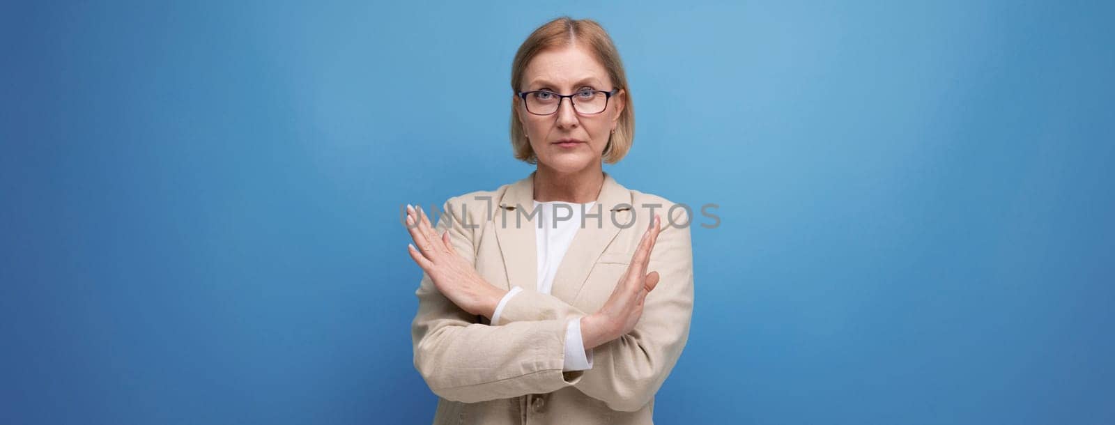 portrait of a business mature adult woman in a classic jacket with crossed arms on a bright background with copy space.