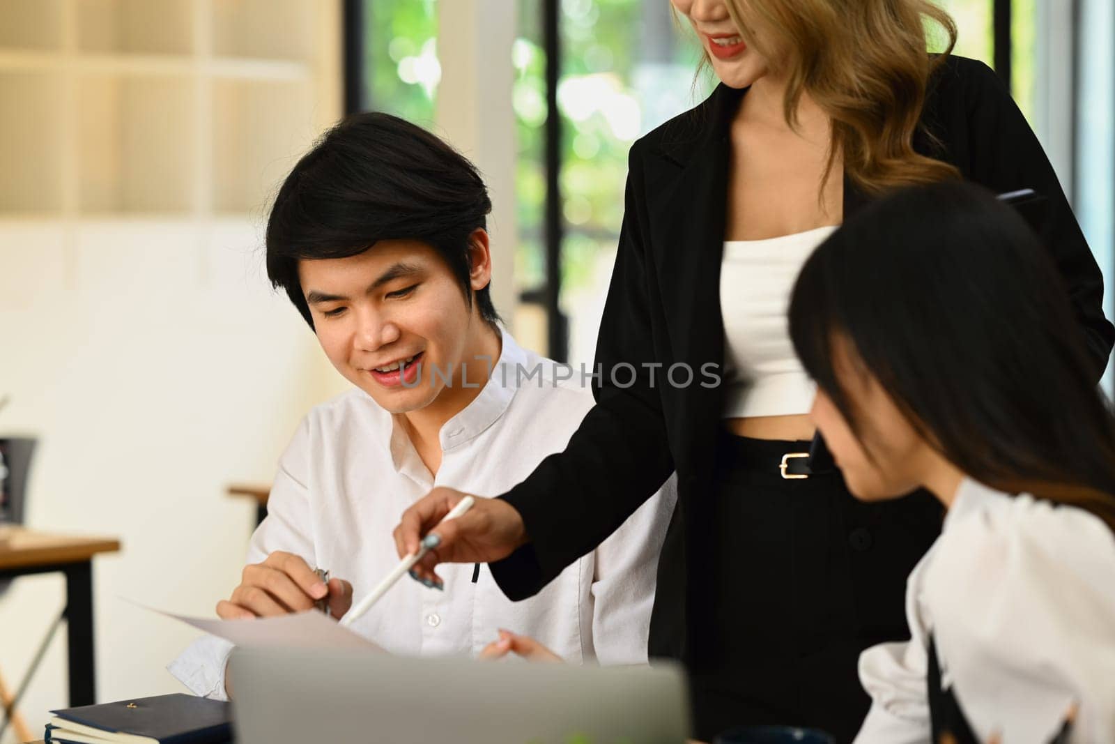 Businesspeople are looking at laptop screen, analyzing sales statistics document at co working space.