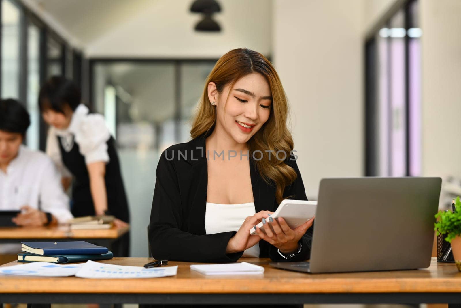 Millennial asian female manager using calculator and checking financial reports at office desk.