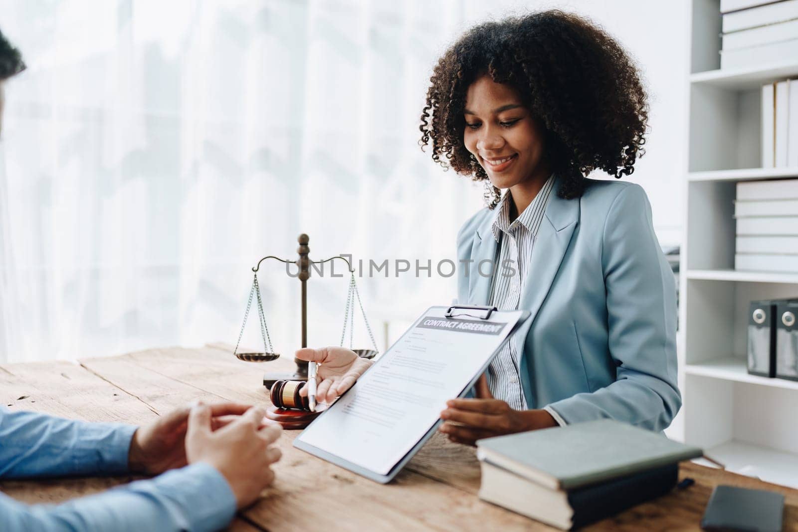 Young African American lawyer studying a case for a client and signing a legal contract to fight her opponent in court. Legal and lawyer concepts. by Manastrong