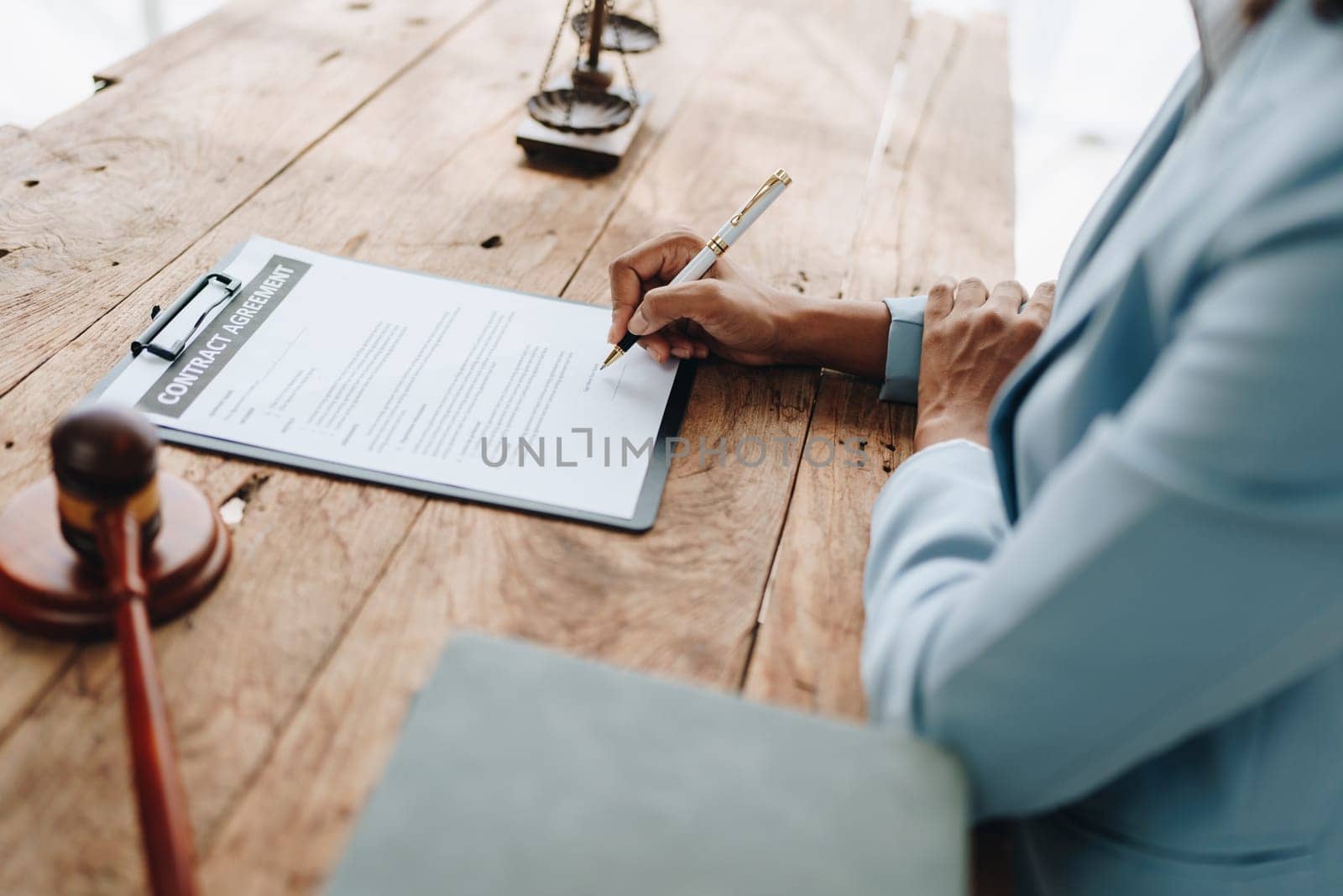 Young African American lawyer studying a case for a client and signing a legal contract to fight her opponent in court. Legal and lawyer concepts. by Manastrong