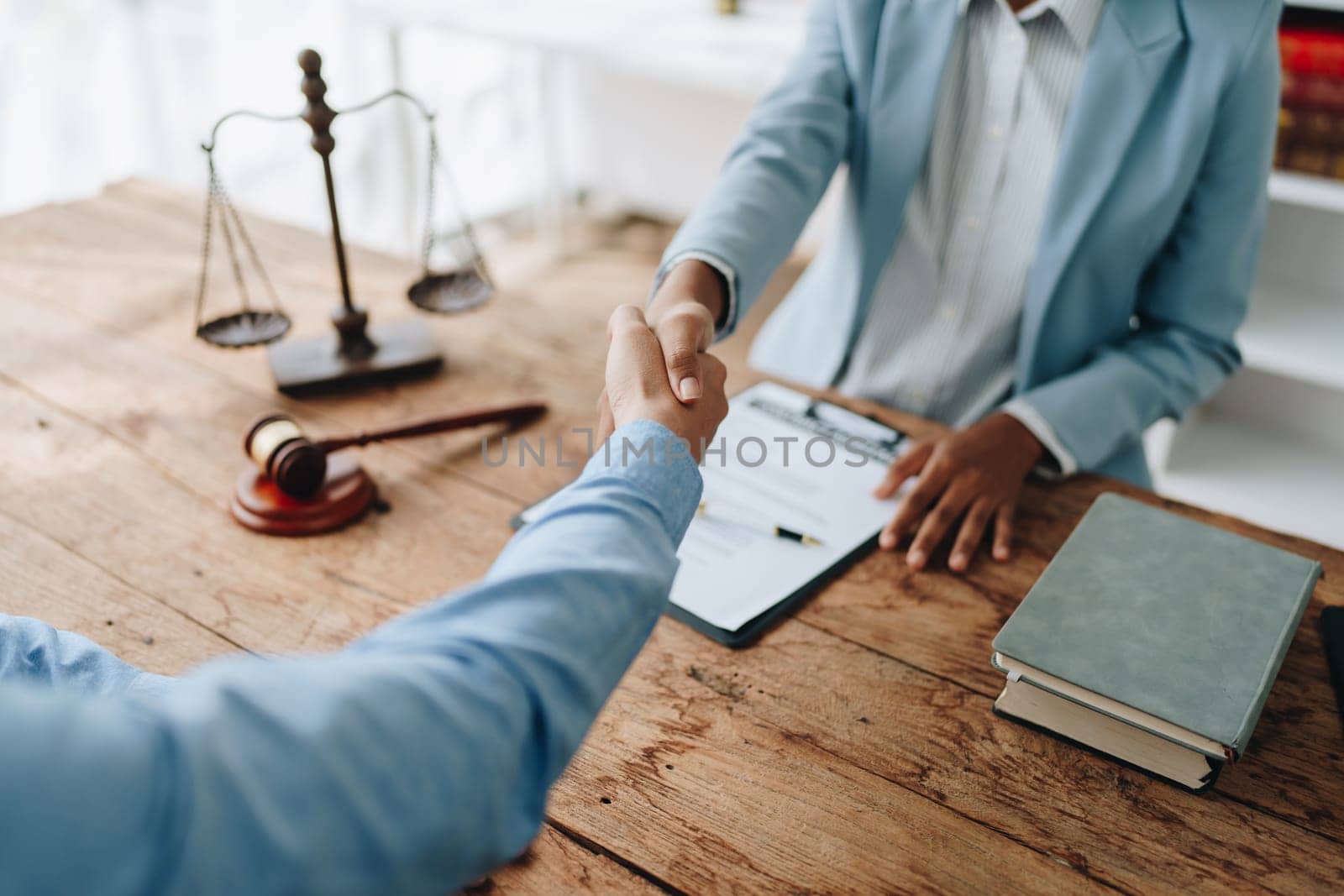 Law, consultation, agreement, contract, lawyer or attorney shakes hands to agree on the client's offer to be hired to fight the parties in court. by Manastrong