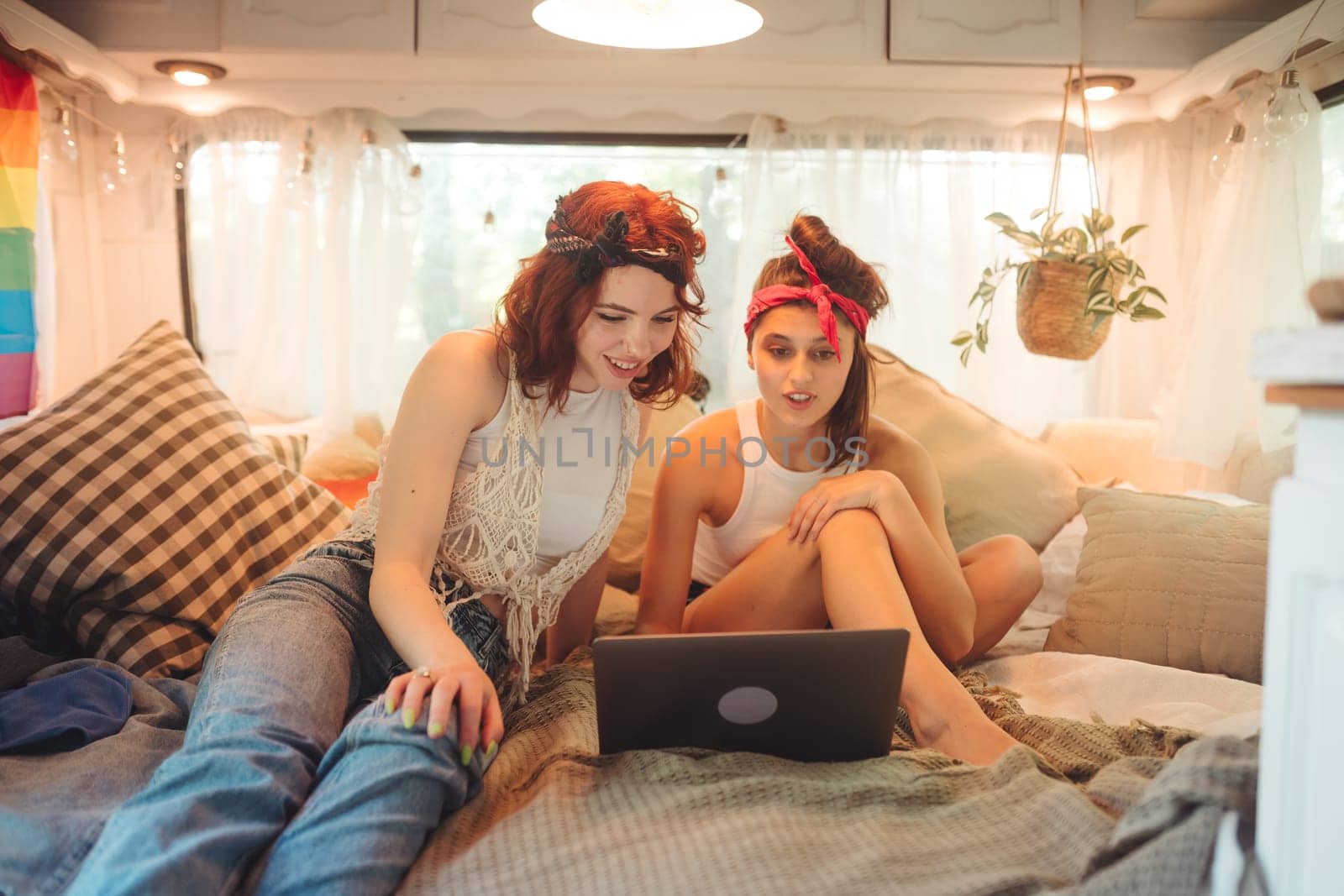 Portrait of a cute lesbian couple. Two girls spend time tenderly together watching movie on laptop in a camper trailer. Love and attitude. LGBT concept. High quality photo